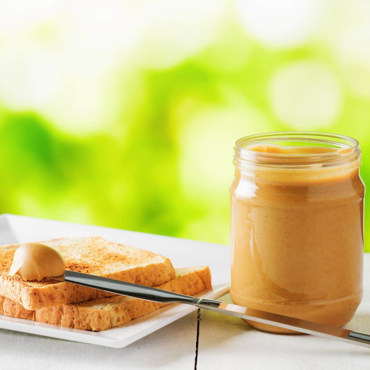 jar of peanut butter with toast on plate.