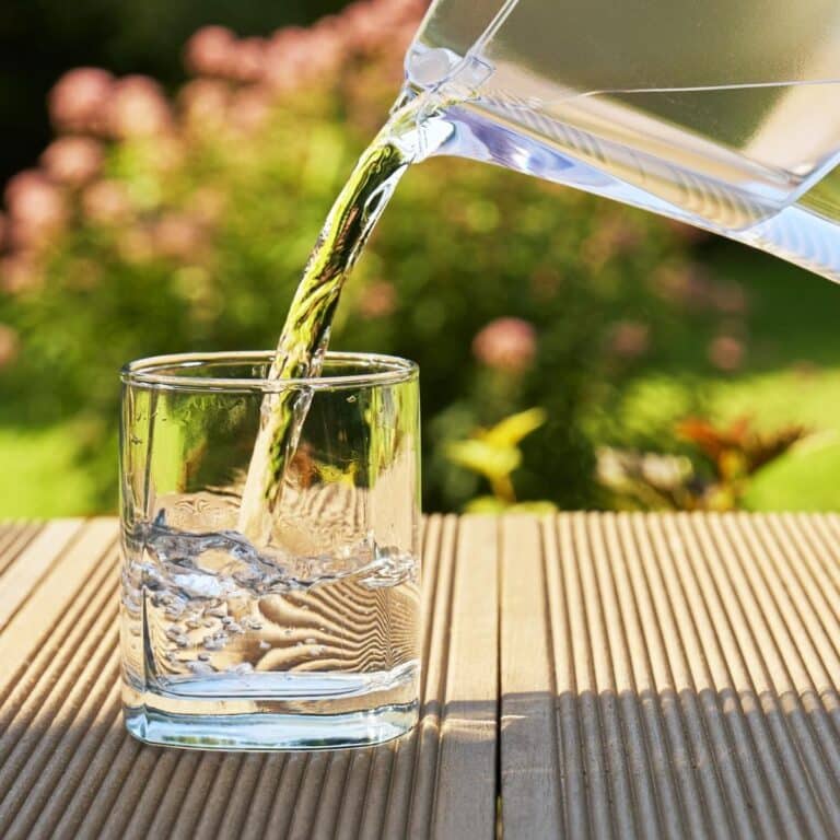 Pouring clear filtered water from a water filtration jug into a glass