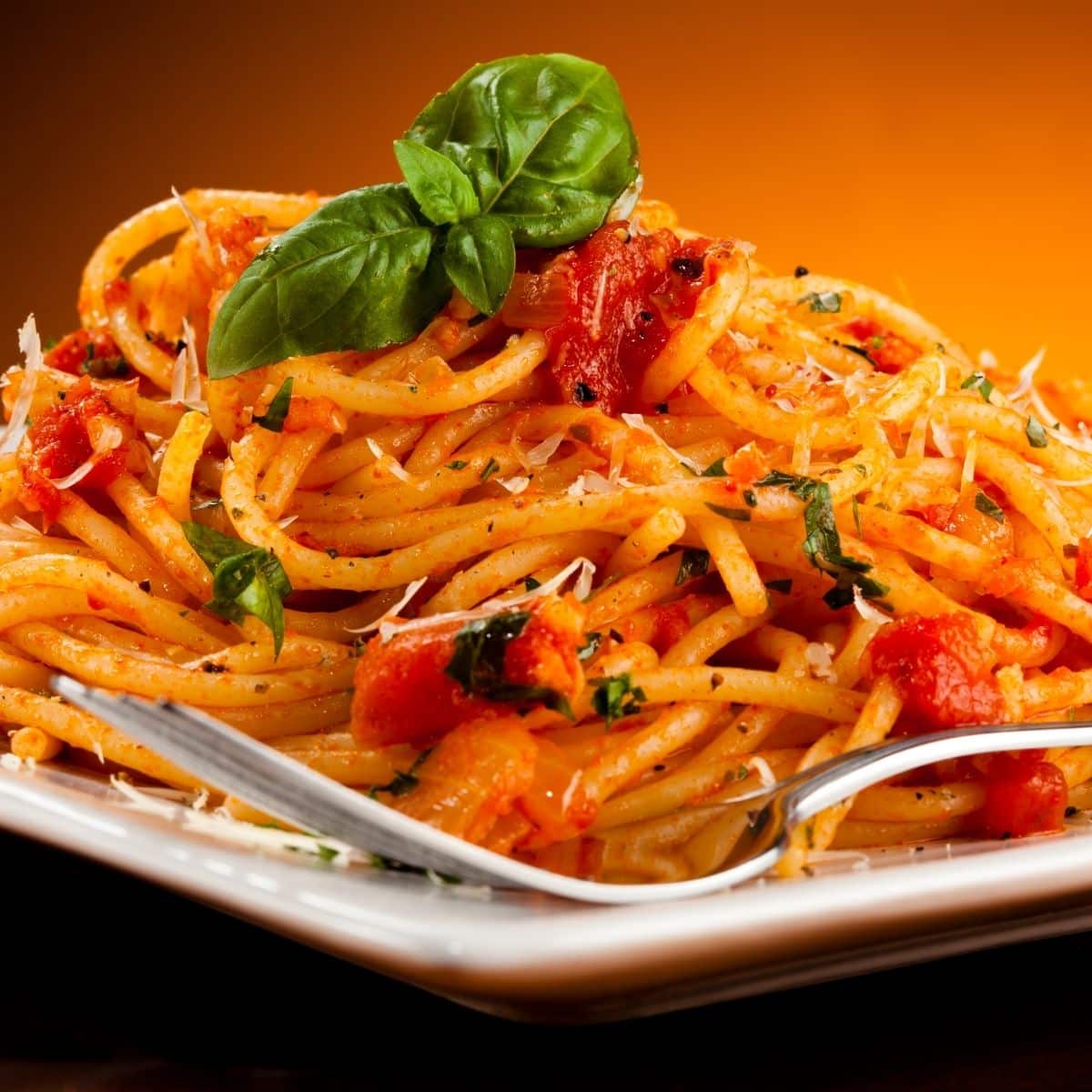 plate of spaghetti with red tomato sauce and basil garnish.
