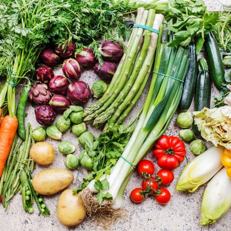 Fresh vegetables of different types and varieties lie in a semicircle on the left on a stone background
