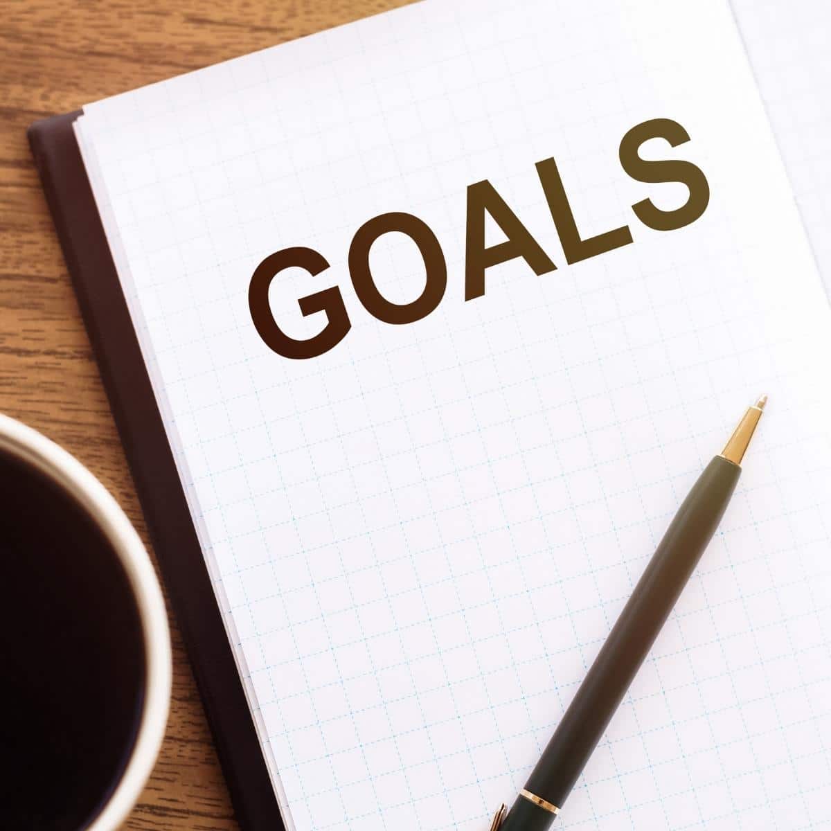 Top view of the text GOALS in notebook and a pencil on wooden desk