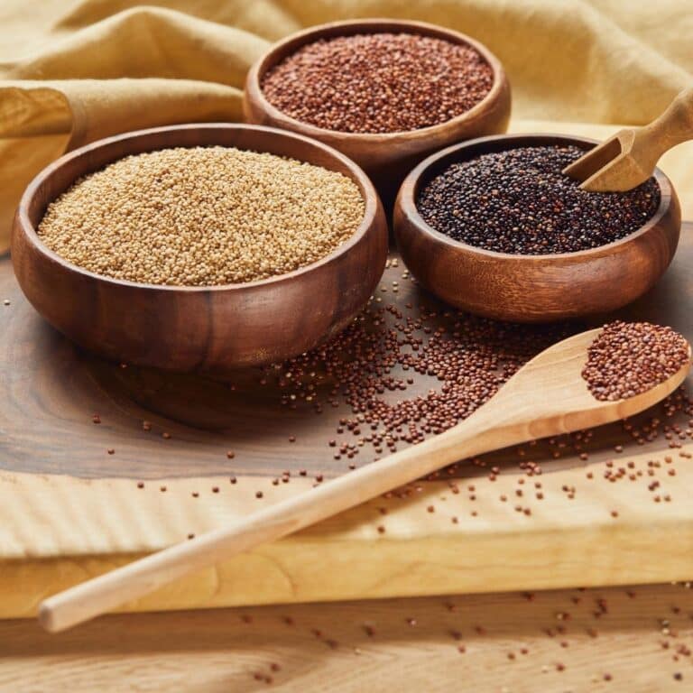 White, black and red quinoa in wooden bowls and spoon
