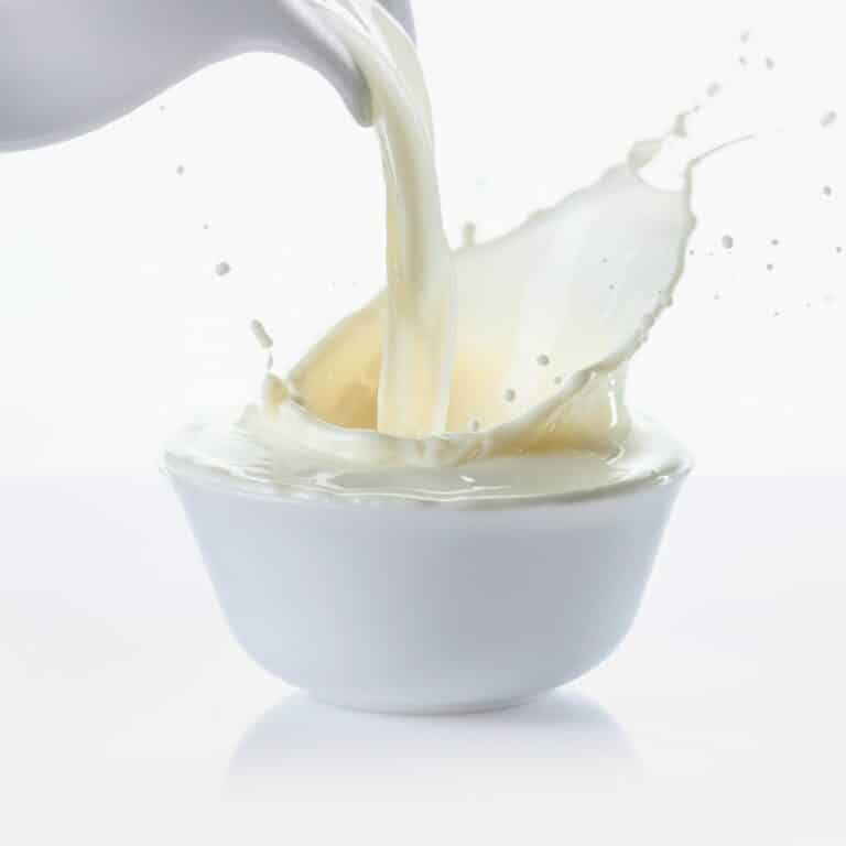 Pouring milk from jug in bowl