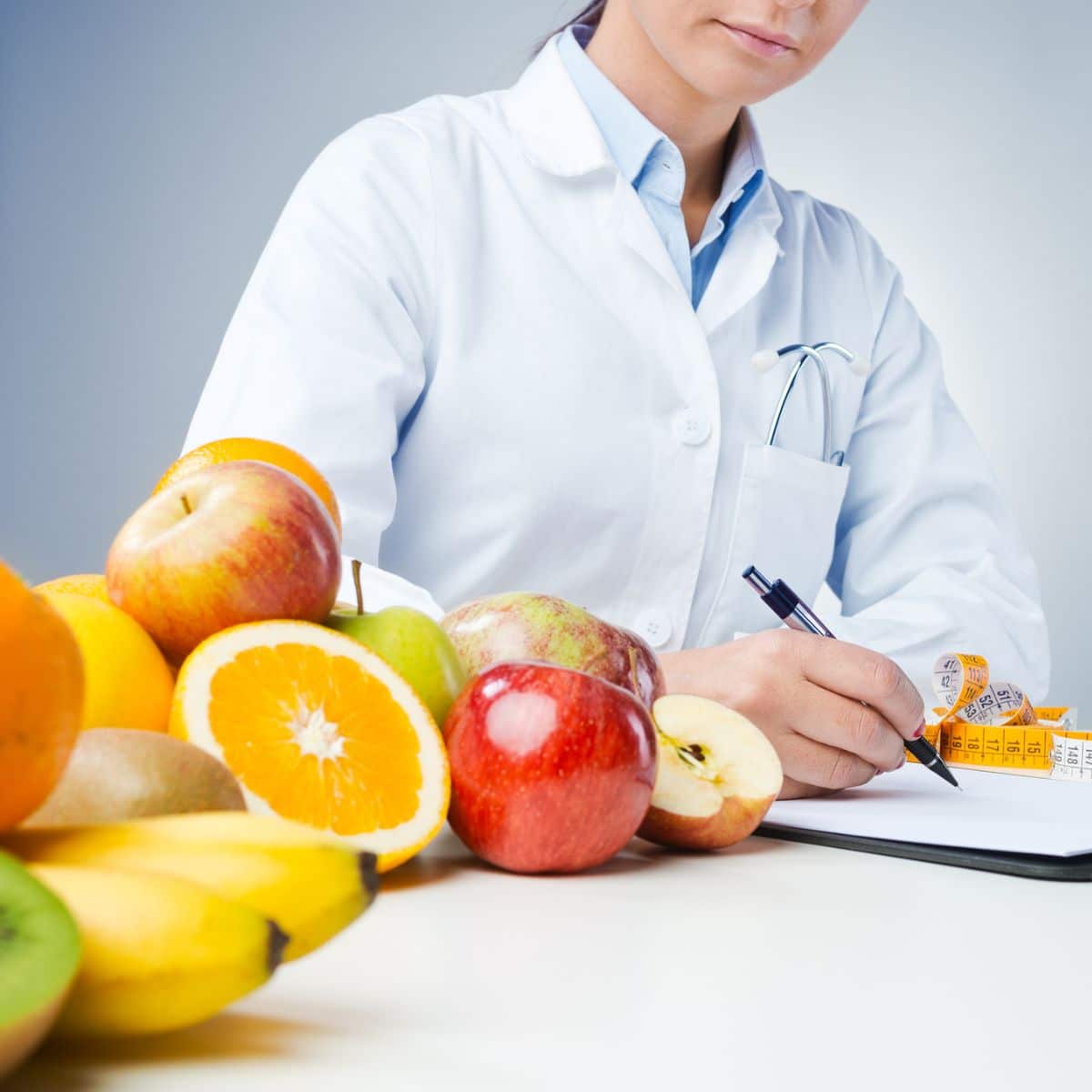 Professional nutritionist writing medical records with fruits on her side