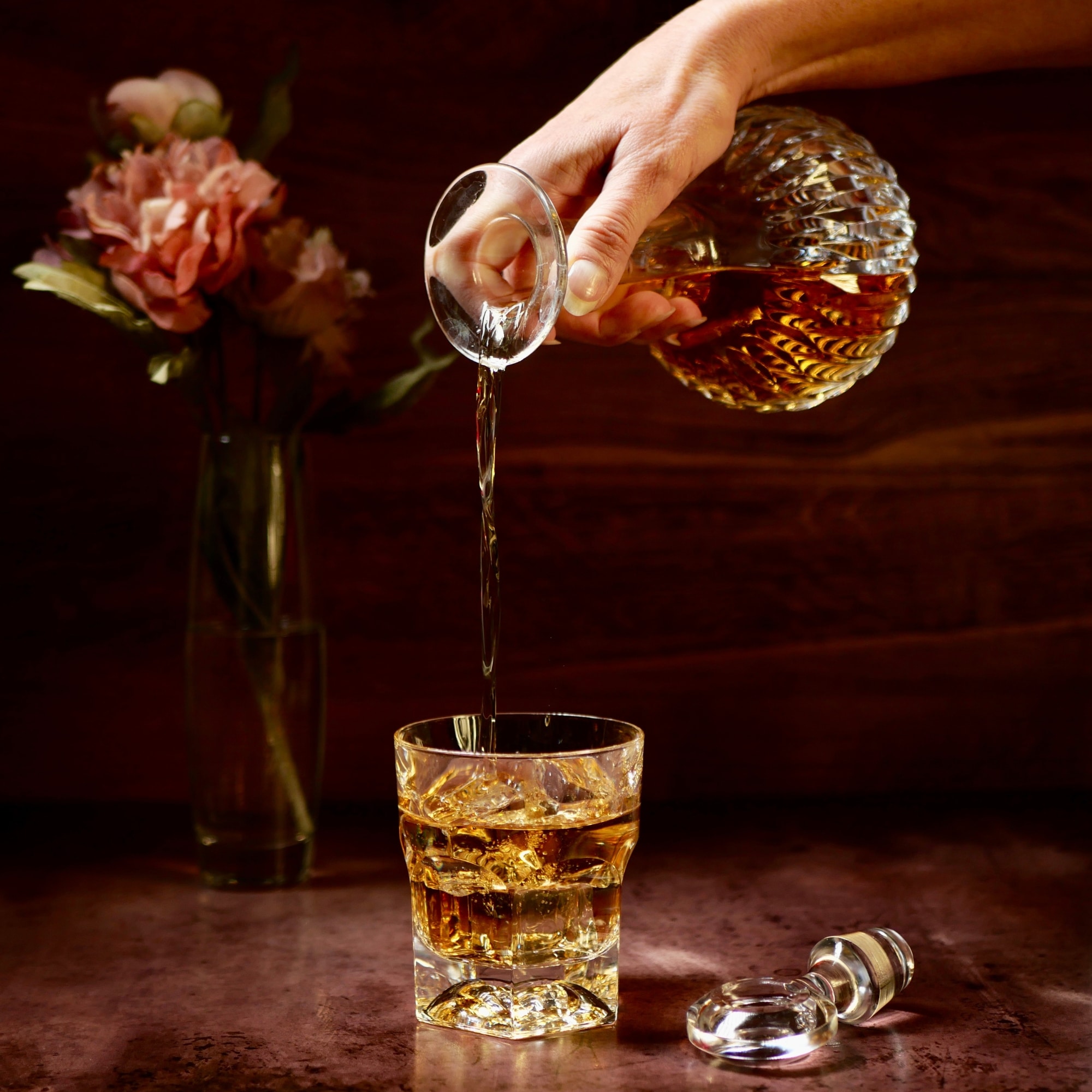 a person pouring a glass of whiskey into a glass