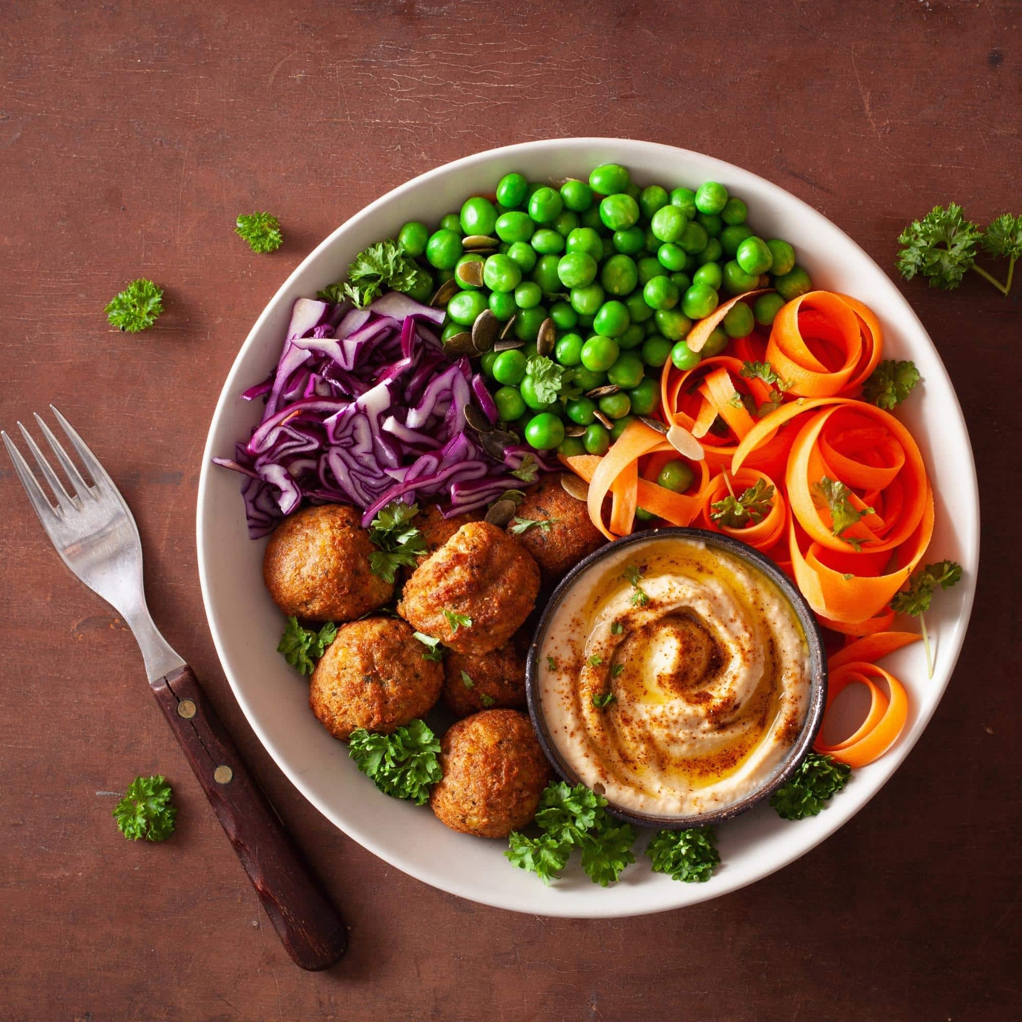 Healthy Vegan Lunch Bowl falafel humus carrot ribbons, cabbage and peas