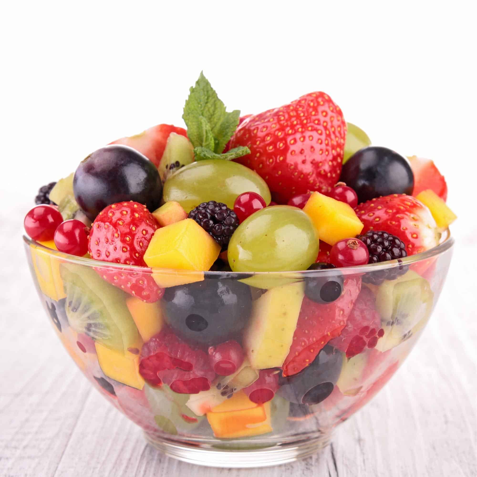 a glass bowl filled with fruit on a wooden table