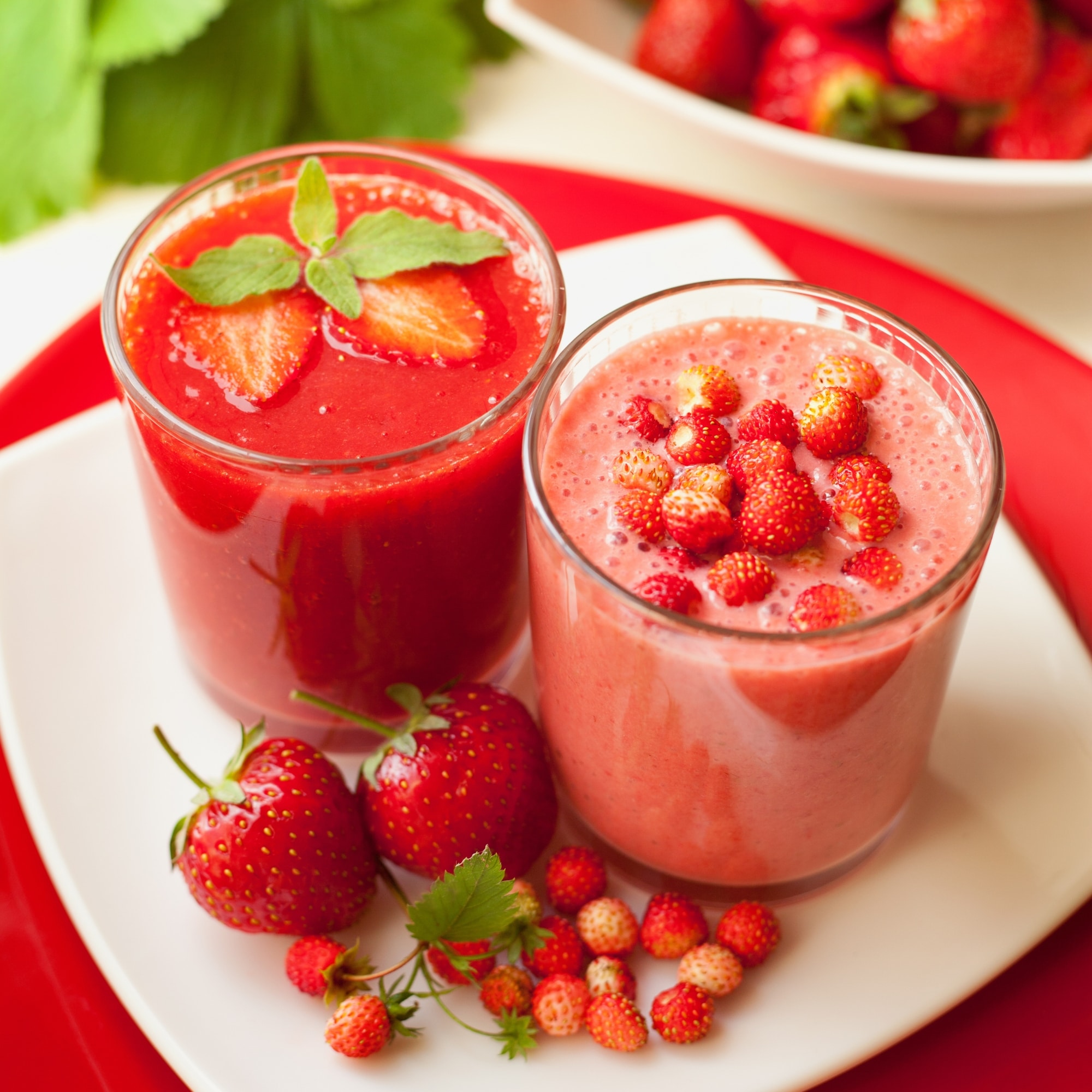 two glasses of strawberry smoothie on a white plate