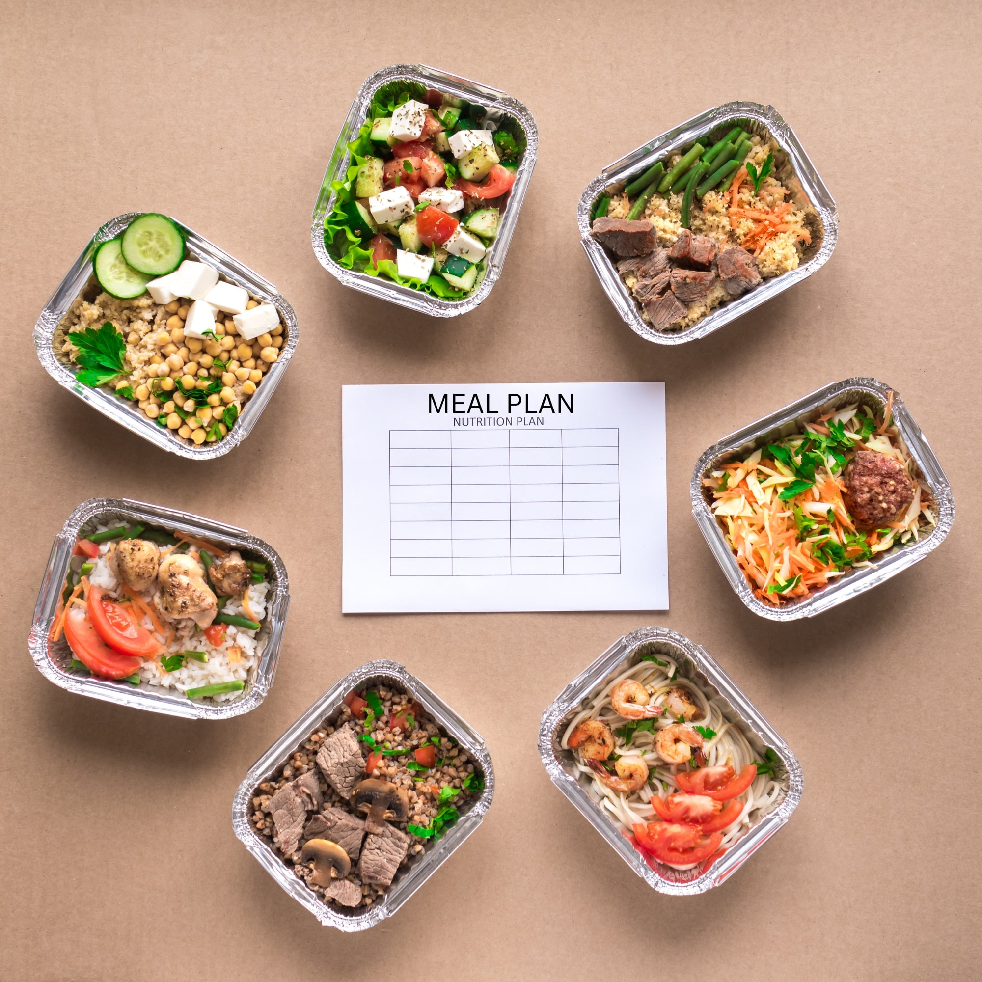 meal prep containers arranged in a grid on a brown background with a list of ingredients on a piece of paper