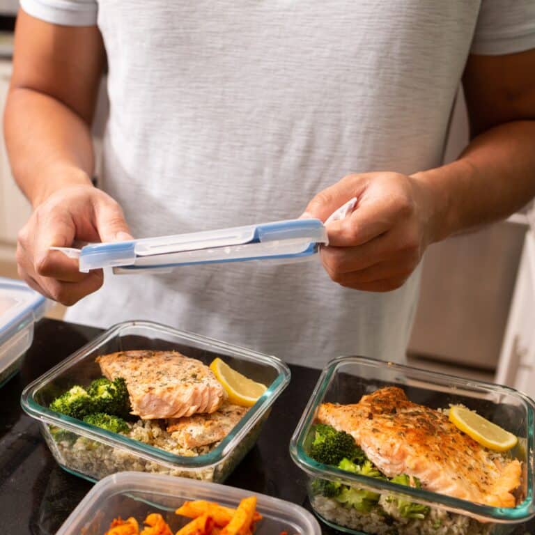 a person holding a container of food in front of four containers of food.