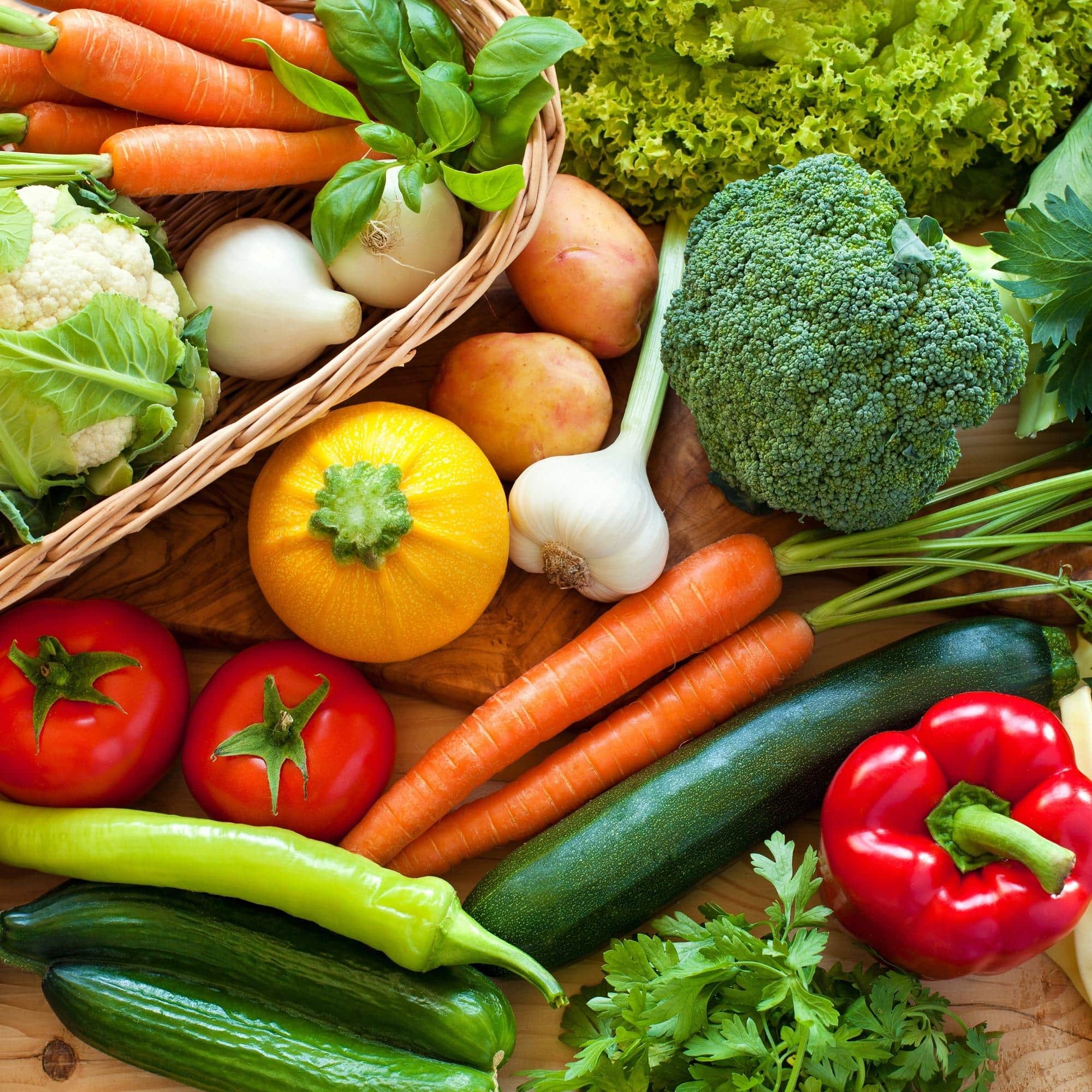 an assortment of fresh vegetables on a wooden cutting board