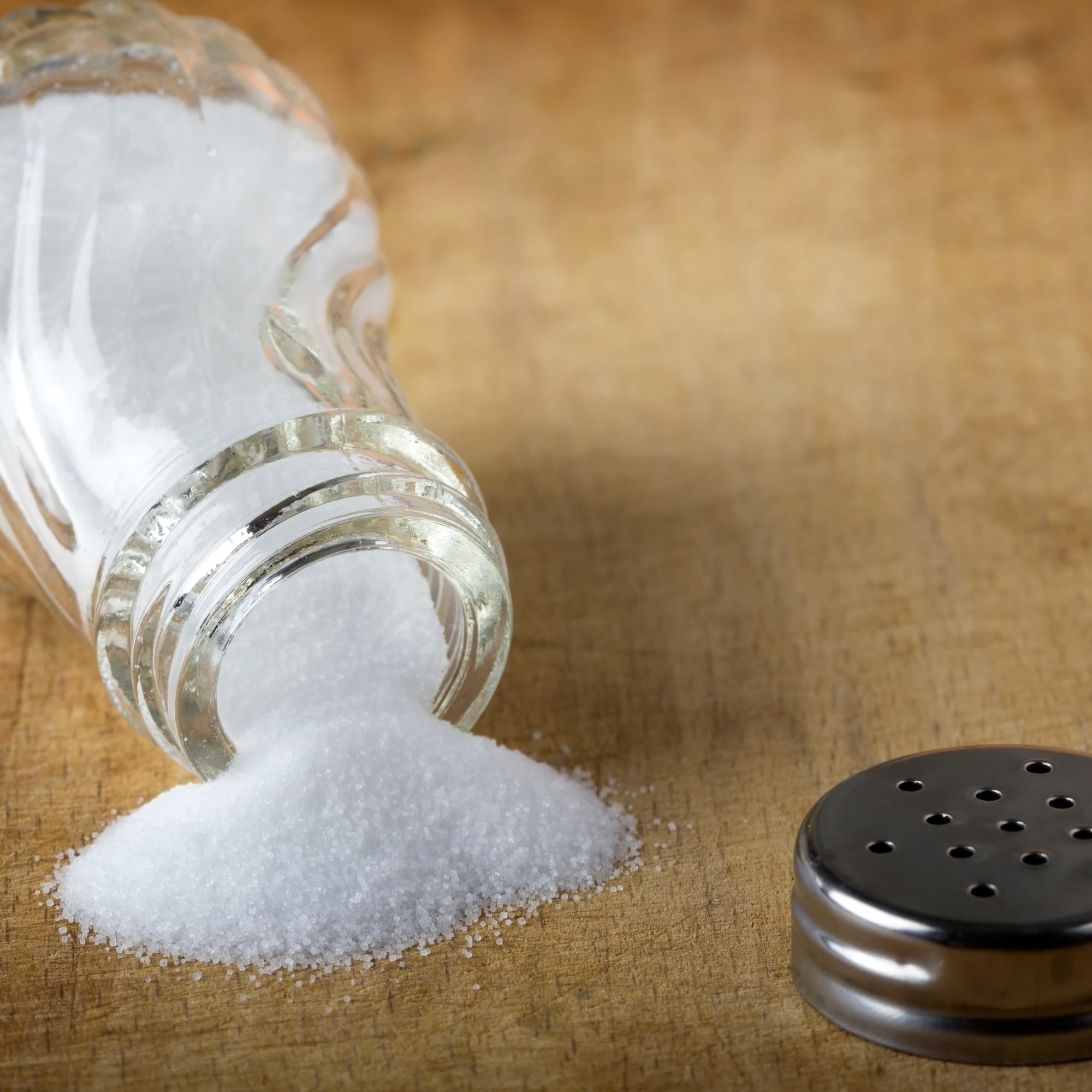 a salt shaker and salt on a wooden table