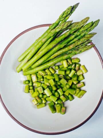 Fresh washed Asparagus with water drops in white bowl, part of the cut, the other bunch.