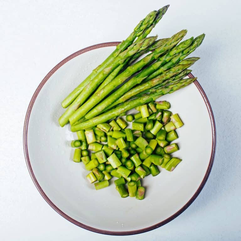 Fresh washed Asparagus with water drops in white bowl, part of the cut, the other bunch.