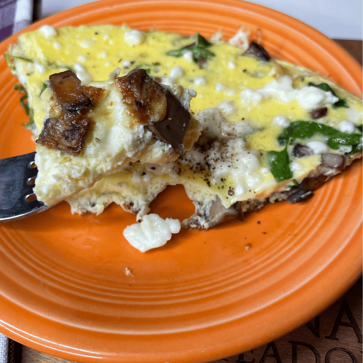 egg arugula mushroom frittata on plate with fork full close up.