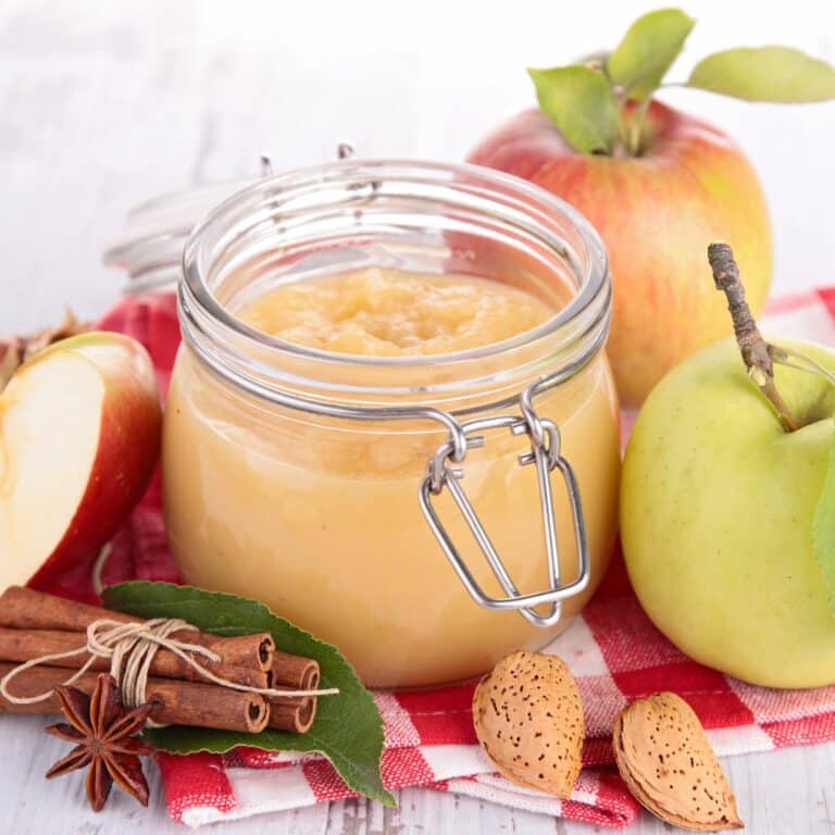 a jar of apple butter on a red checkered cloth