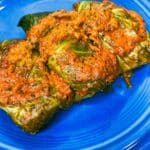cabbage rolls that are done plated on a blue plate with sauce