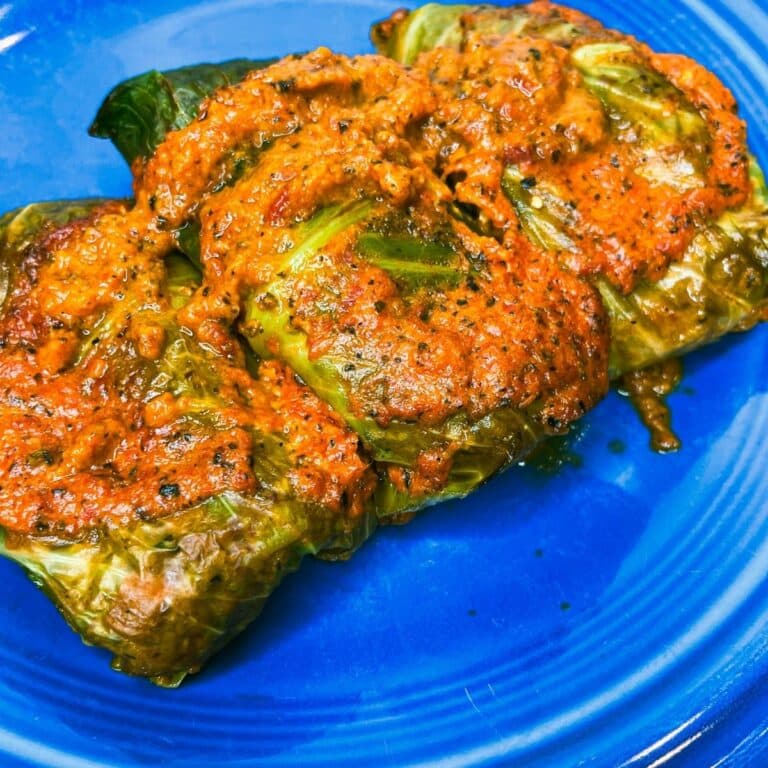 cabbage rolls that are done plated on a blue plate with sauce
