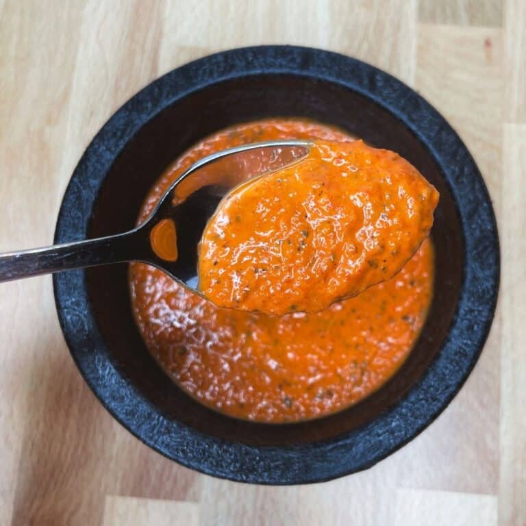 roasted red pepper sauce on a spoon in a black serving dish