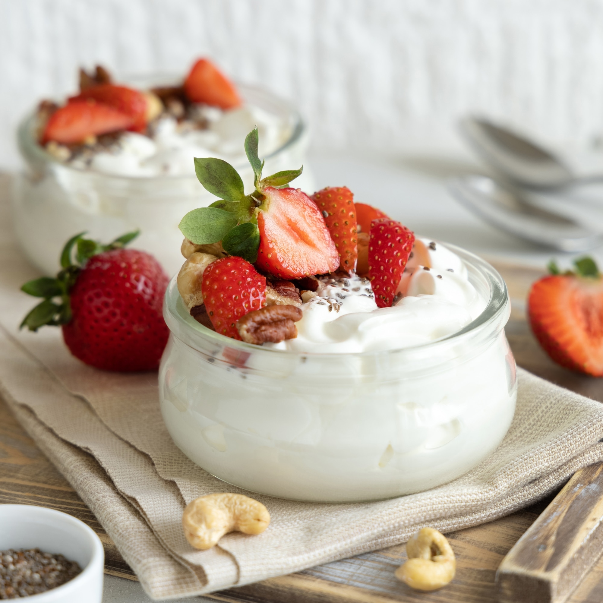 Glass jars of Greek yogurt, nuts and strawberries on a tray