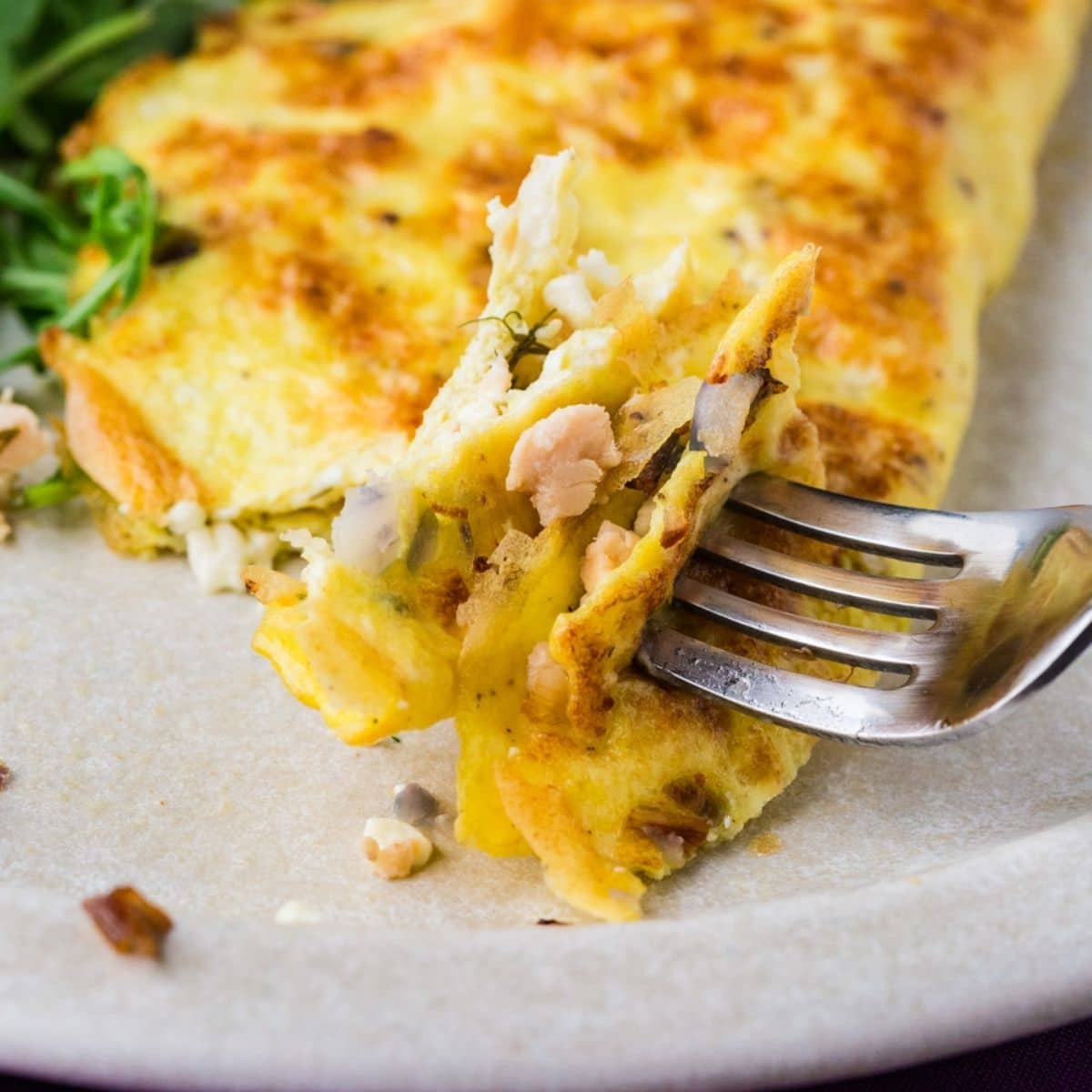 salmon omelette on fork showing salmon, onion and dill.