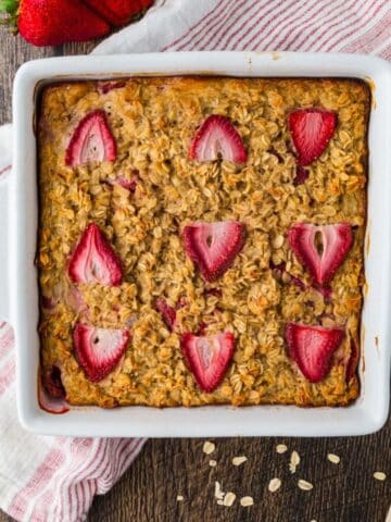 Overhead view of pan of strawberry baked oatmeal with nine strawberries on top of it.