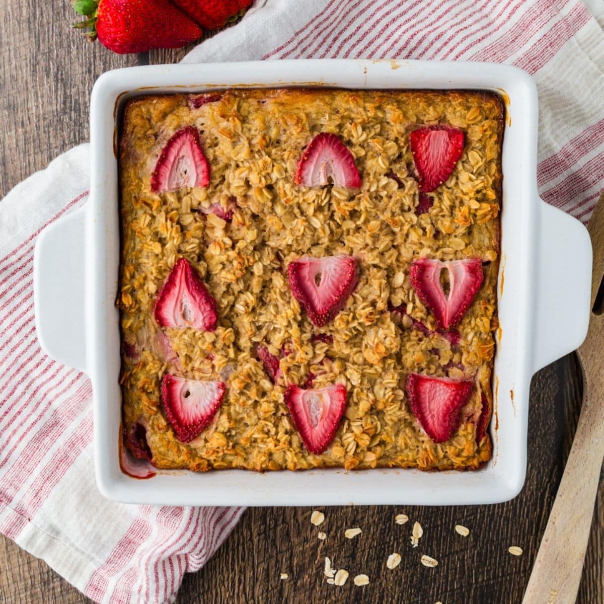 Overhead view of pan of strawberry baked oatmeal with nine strawberries on top of it.