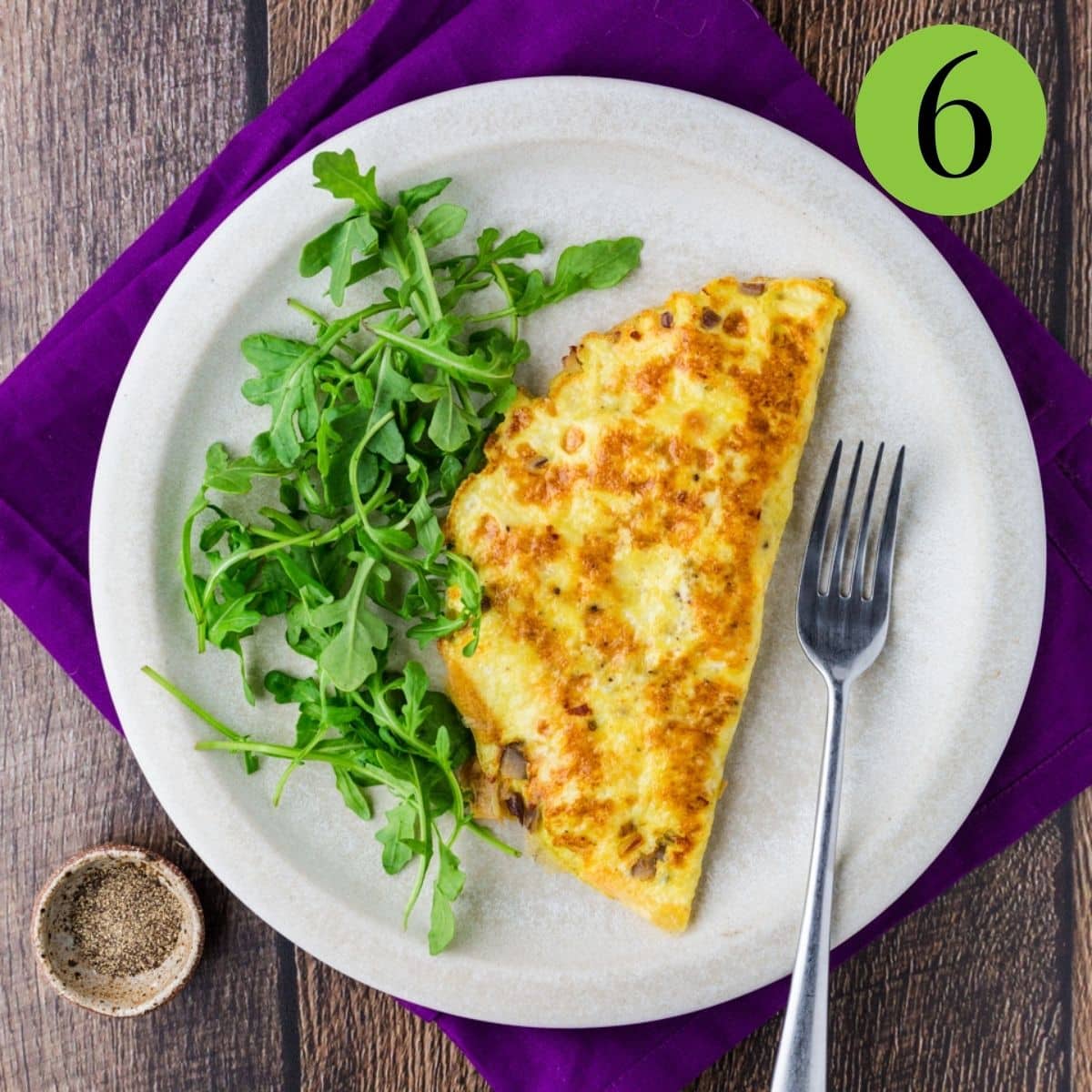 omelette on plate with greens and a fork
