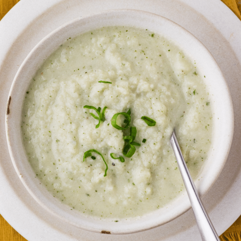 Cauliflower Goat Cheese Soup in a white bowl ready to be served on a plate.
