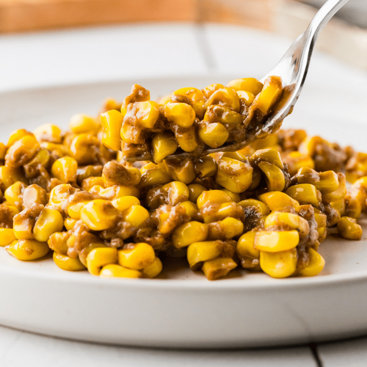 Skillet Corn in a white dish with some on a fork ready to be served