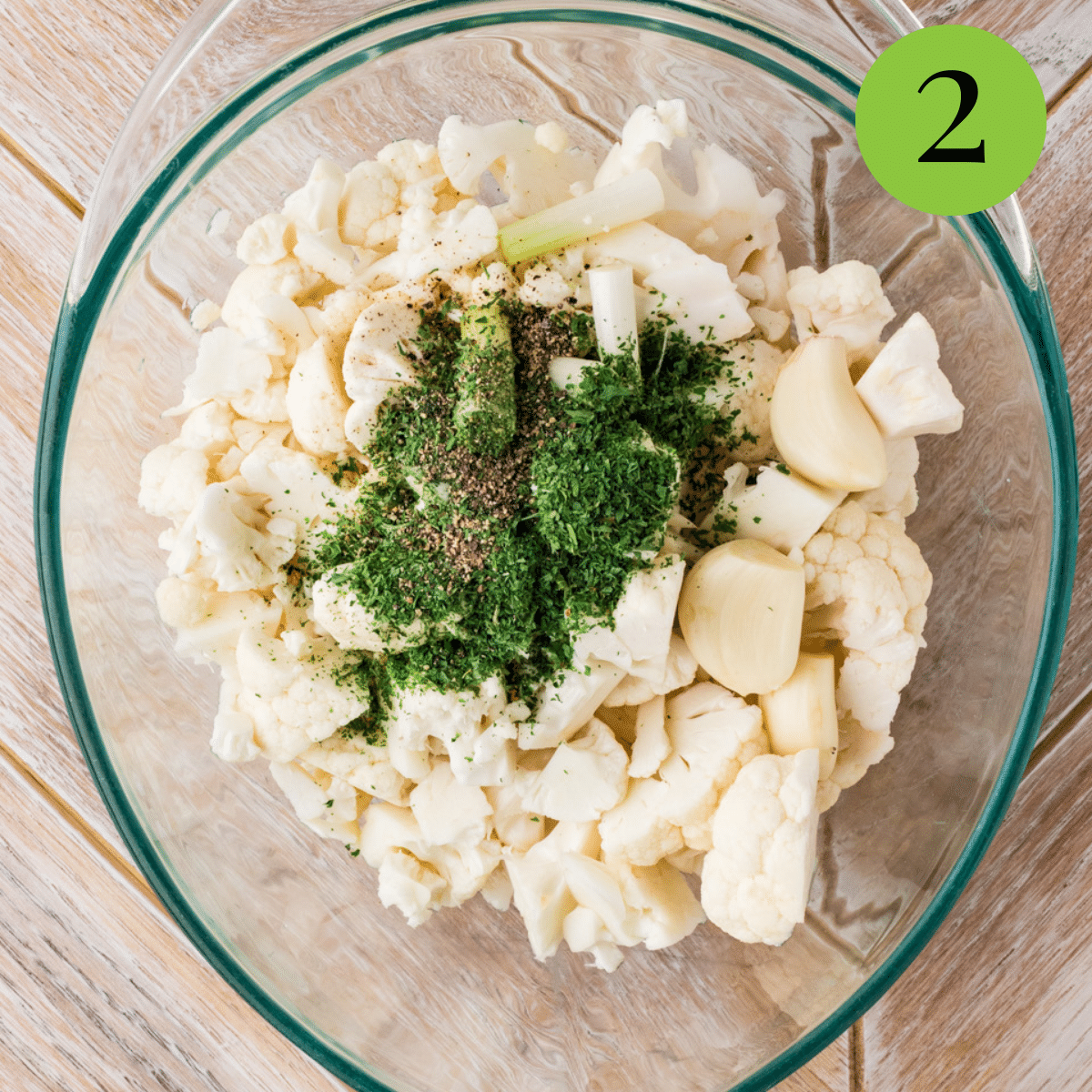 Cauliflower and parsley being put in a glass bowl to begin making the soup. 