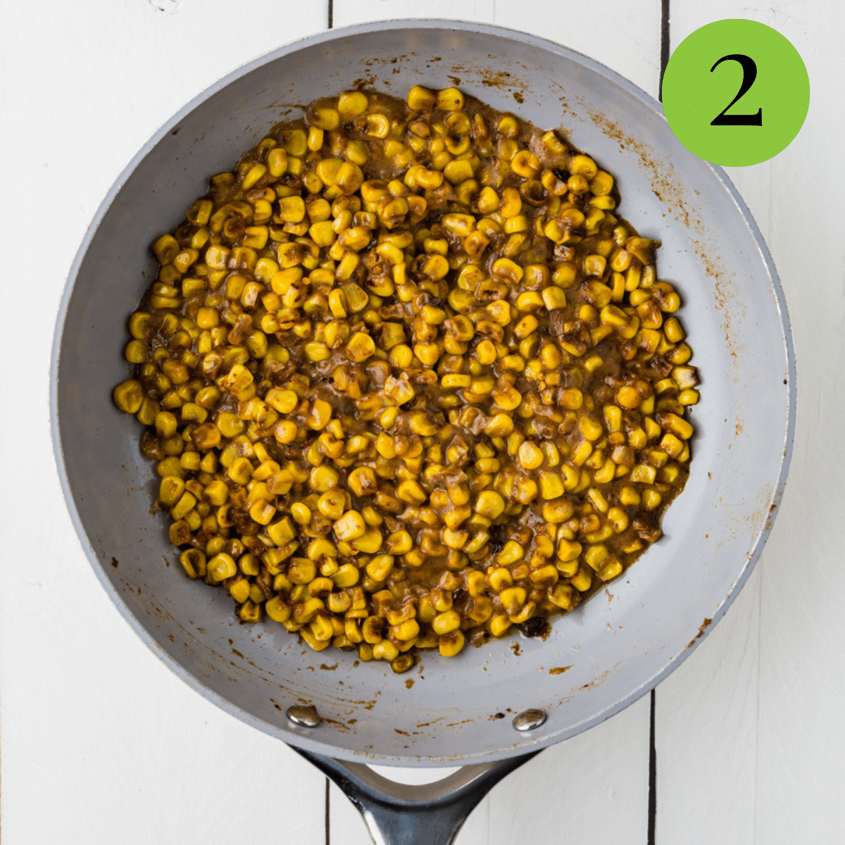 Corn, pepper, sugar, butter, cumin, and water in a 10 inch skillet as Skillet Corn is being made. 