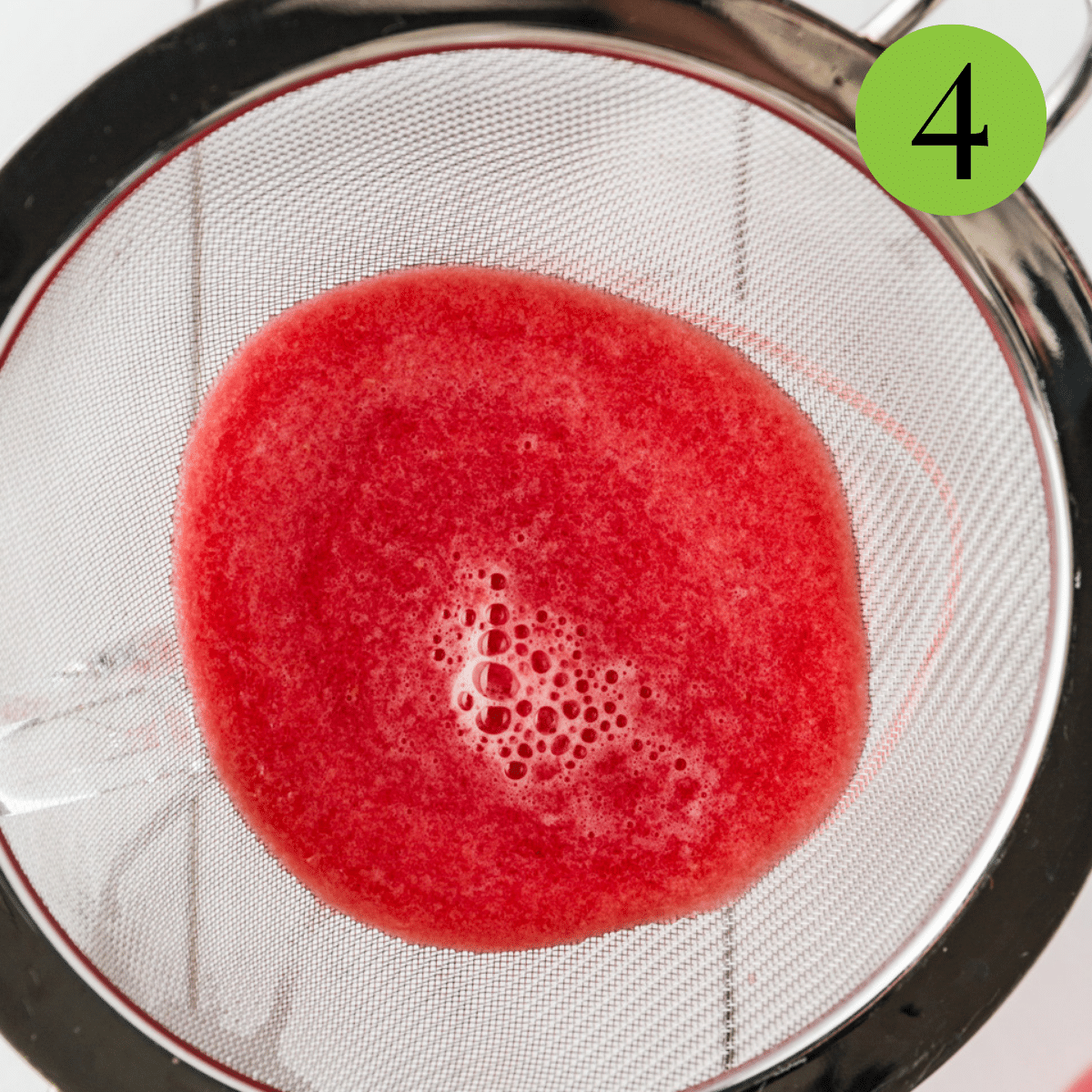Watermelon in a strainer being strained for Watermelon Mint Lemonade. 