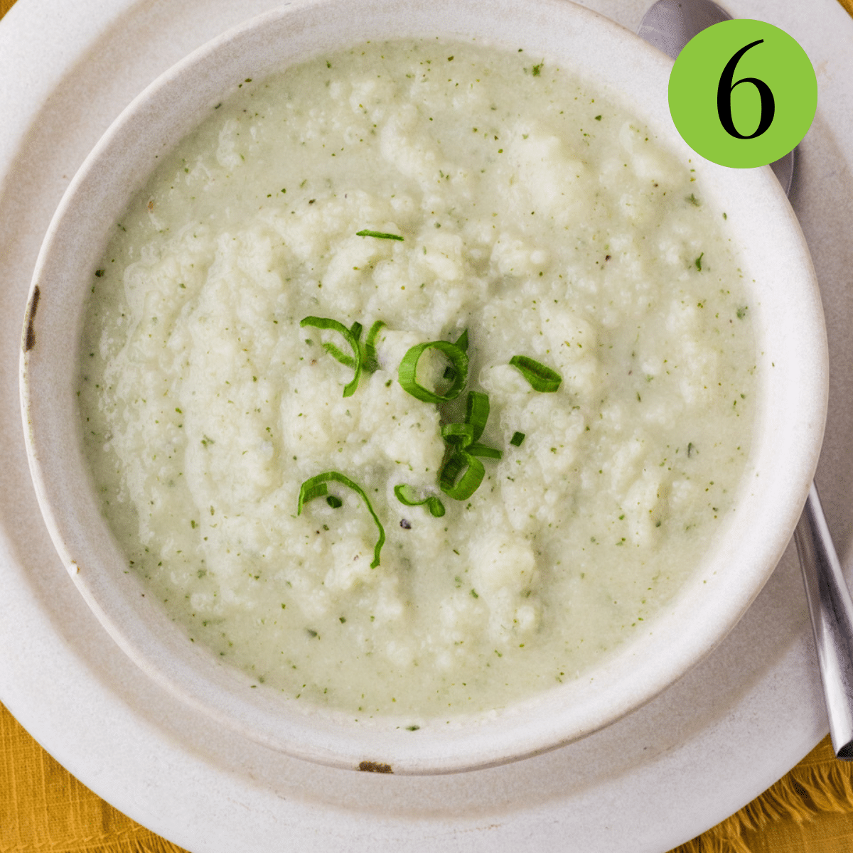 Cauliflower Goat Cheese Soup served on a white bowl and plate with parsley. 