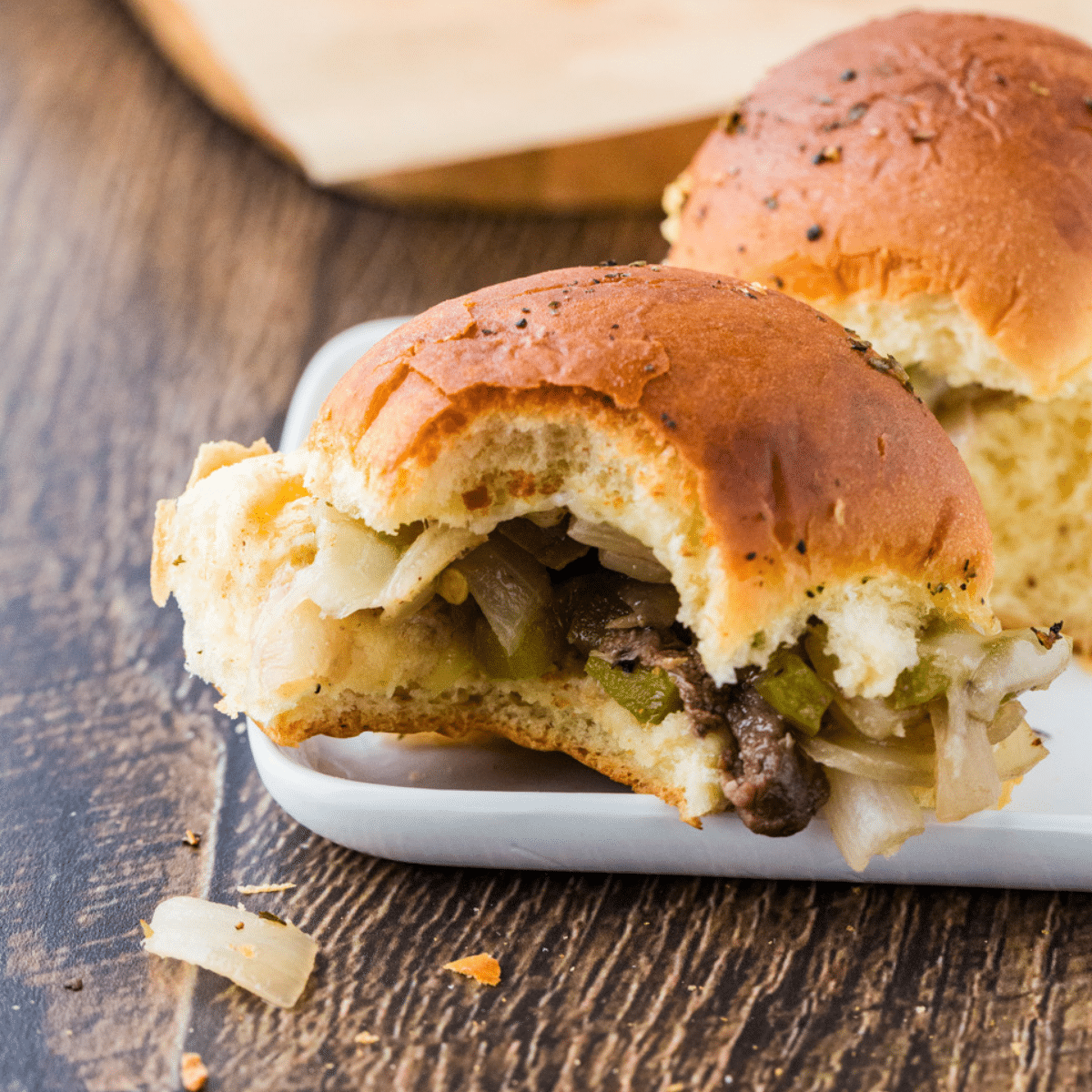 Steak sliders on a plate with a bite taken out of it.
