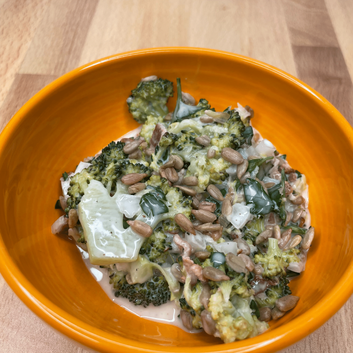 Creamy Broccoli Salad with Bacon in an orange bowl ready to be eaten.