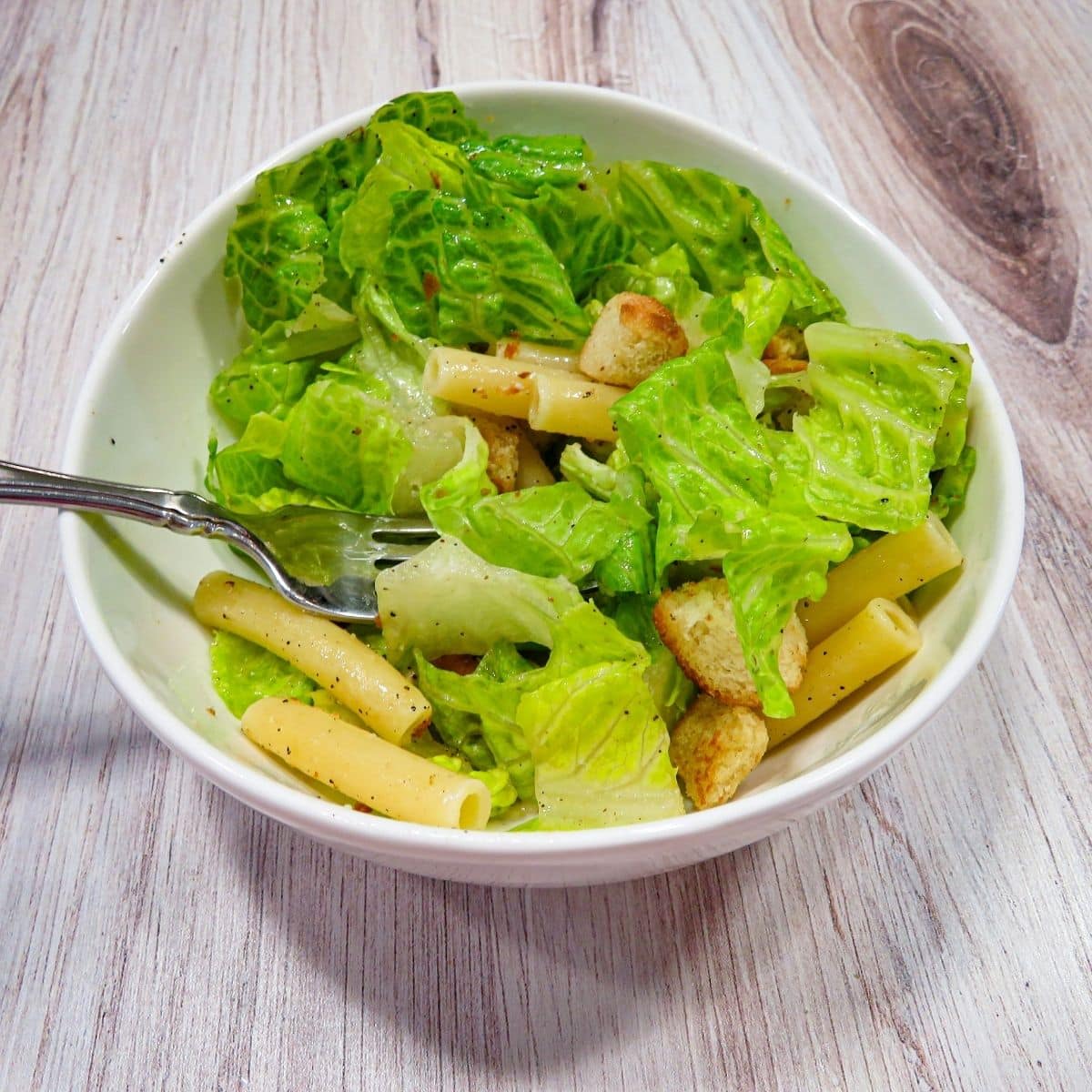 Caesar Pasta Salad in a white bowl to be served. 