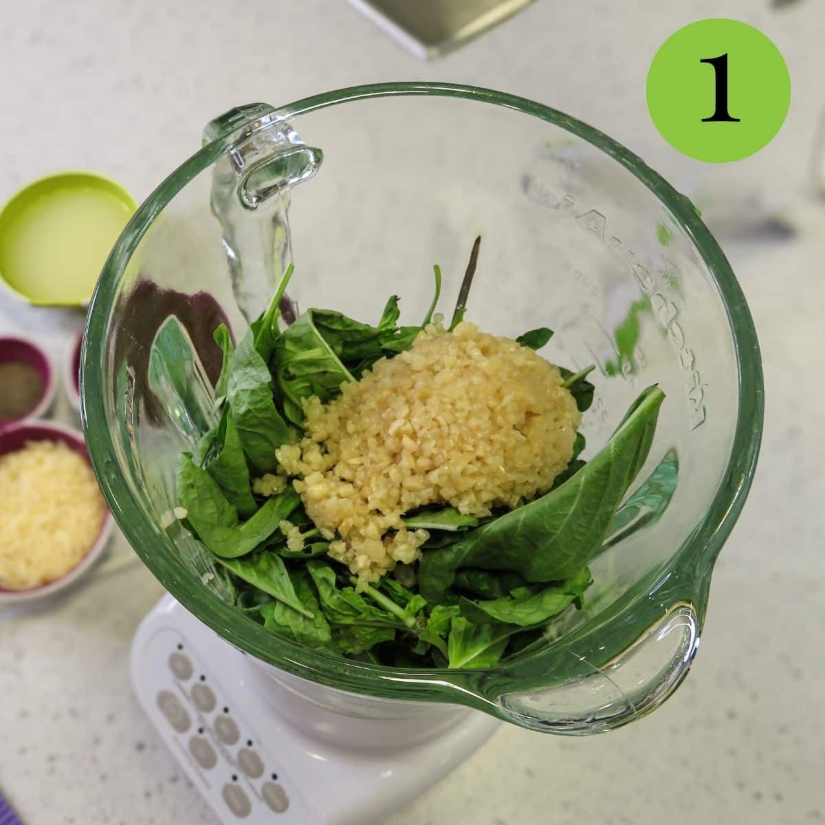 Basil leaves and garlic in a blender. 