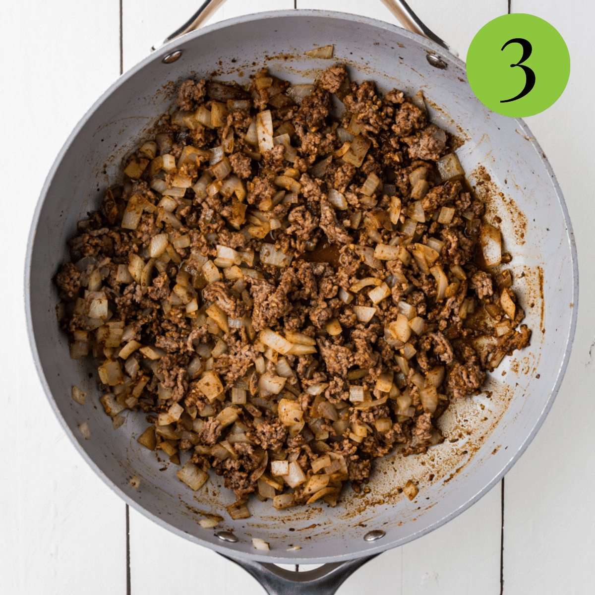 Ground beef and onion in a pan being cooked. 