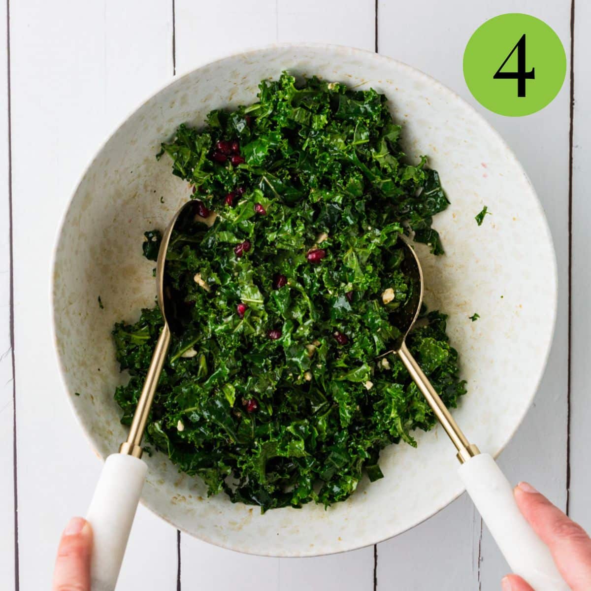 kale salad with pomegranates in bowl mixing